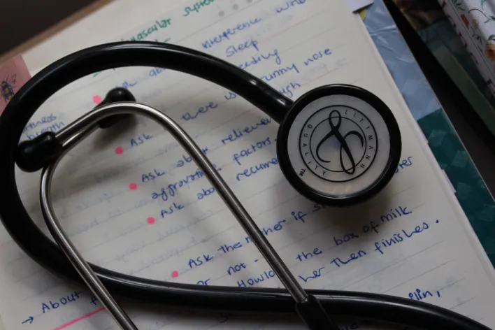 A black stethoscope on handwritten medical notes enhances a study session.