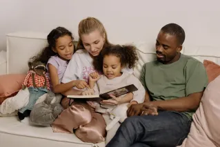 A diverse family enjoying quality time reading a book together in their living room.