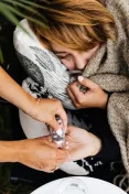 Woman wrapped in a blanket receiving medication assistance, portraying care and health support.