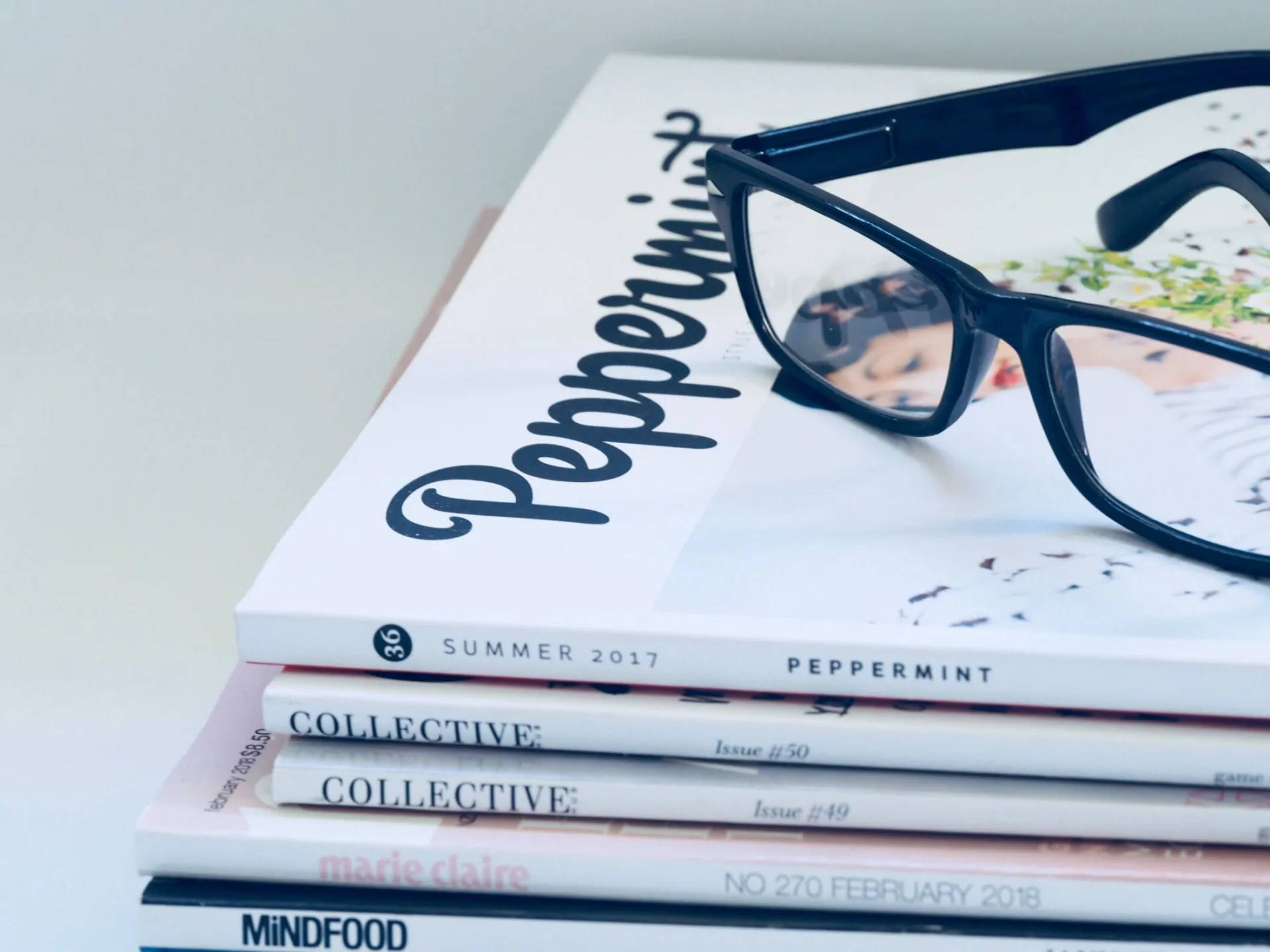 Eyeglasses on a stack of fashion and lifestyle magazines including Peppermint and Collective.