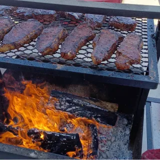 Close-up of seasoned ribs being cooked on a barbecue grill outdoors. Perfect for BBQ lovers.