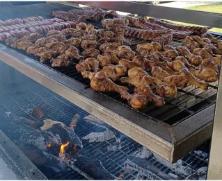 Close-up of smoky grill with meats and colorful vegetables, creating a delicious BBQ scene.