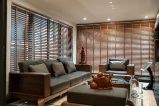 Elegant living room featuring wooden blinds, cozy furniture, and artistic decor for a warm and inviting ambiance.