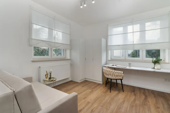 Bright and airy room with modern minimalist decor featuring wooden floors and ample natural light.