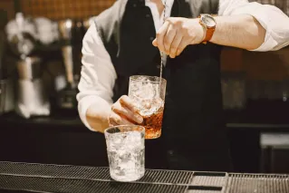 A bartender mixes a classic cocktail with ice in a stylish bar setting.