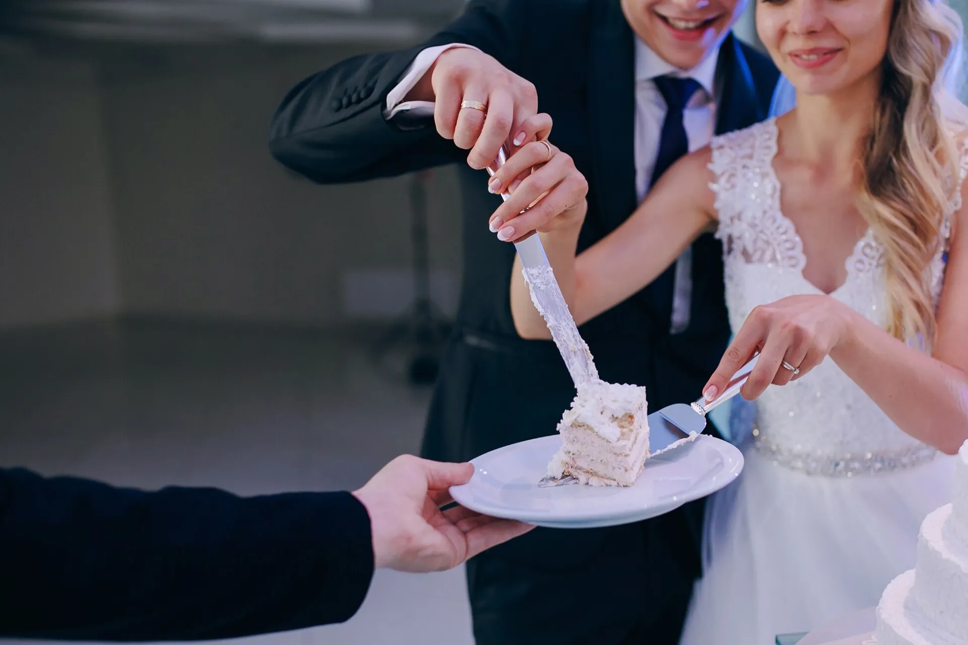 Happy couple and guests raise glasses for a joyful wedding toast indoors.