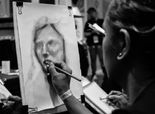 Artist sketching a portrait in monochrome at an indoor workshop.