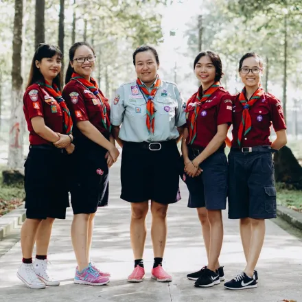 A group of young scout leaders posing in uniform in a forest setting, showcasing teamwork and unity.