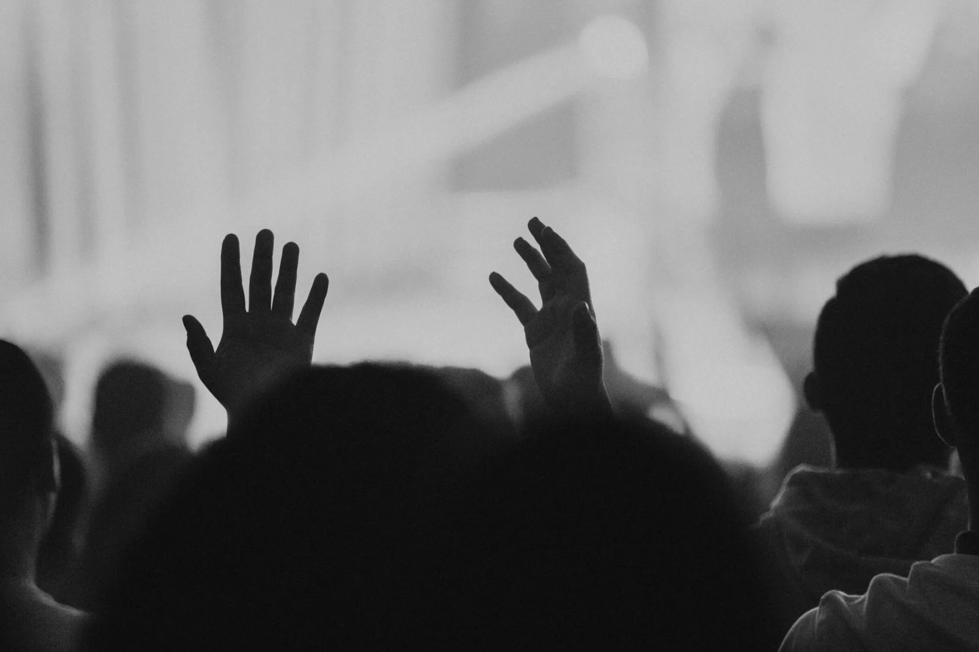 Black and white image of a crowd raising hands in devotion, capturing unity.