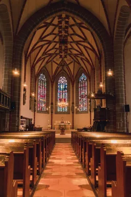 Serene view of a gothic church interior featuring stunning stained glass windows and intricate architecture.