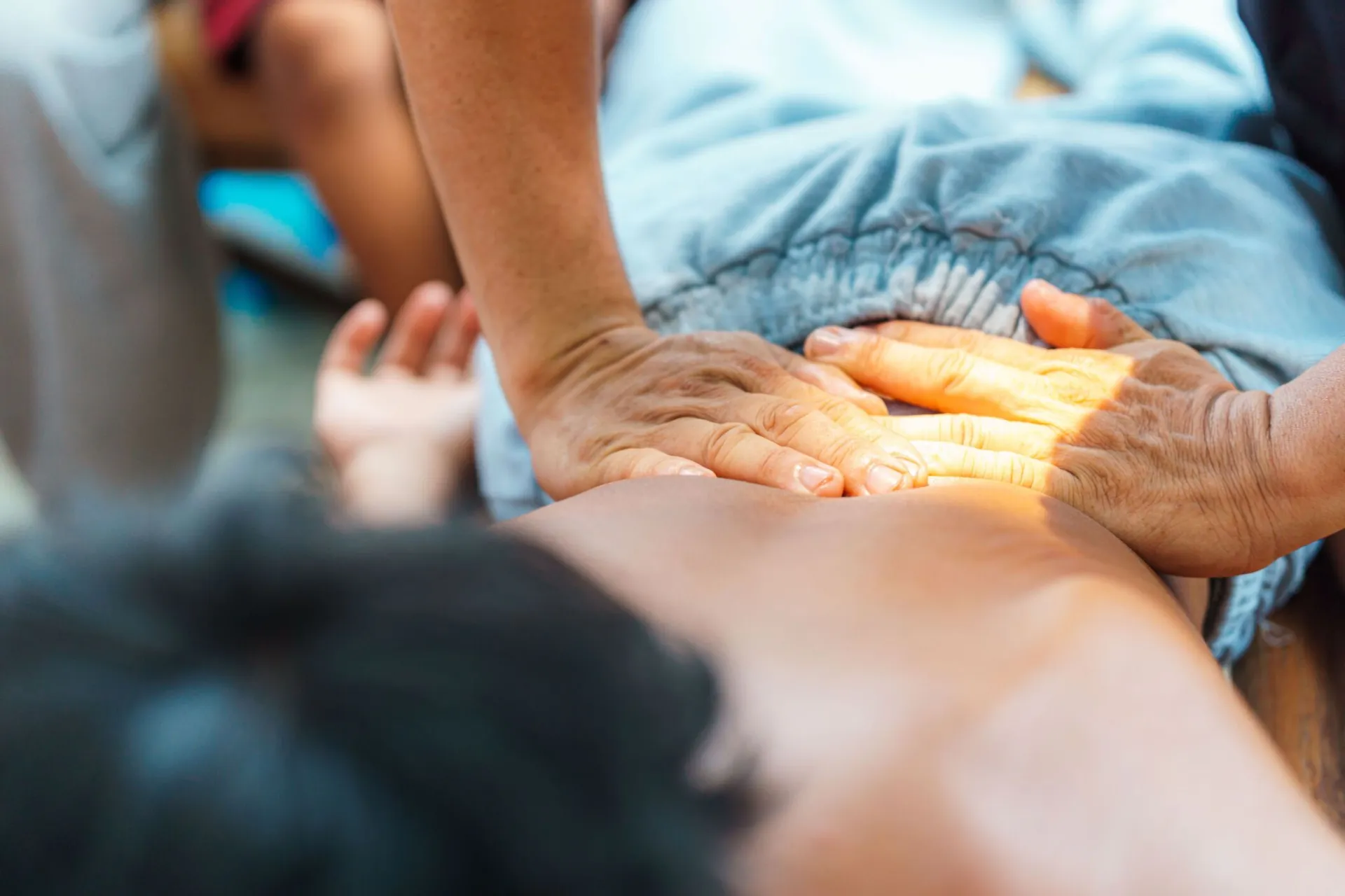 Hands performing a therapeutic massage on a person's back in a serene setting.