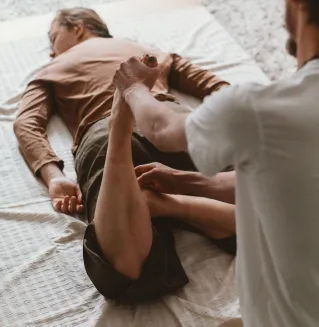 Therapist helps client stretch during a physiotherapy session indoors.
