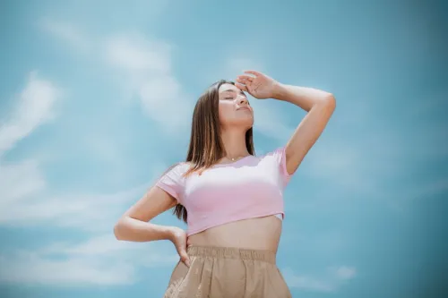Fashion-forward woman posing confidently outdoors against a bright blue sky.