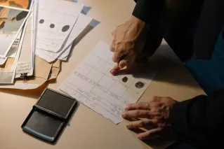 Detailed view of fingerprint analysis on a desk with ink pad and documents, ideal for forensic themes.
