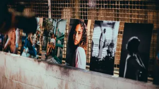 A collection of diverse artistic portraits displayed along a textured wall in Rio de Janeiro.