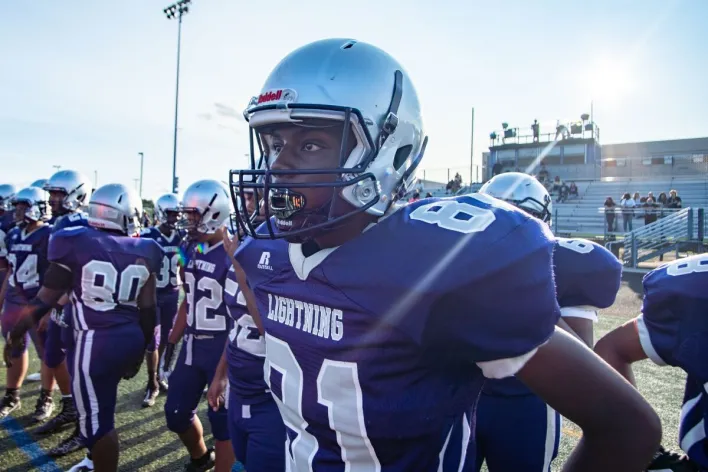 Youth football team in Columbia, MD, preparing for a game on a sunny day.