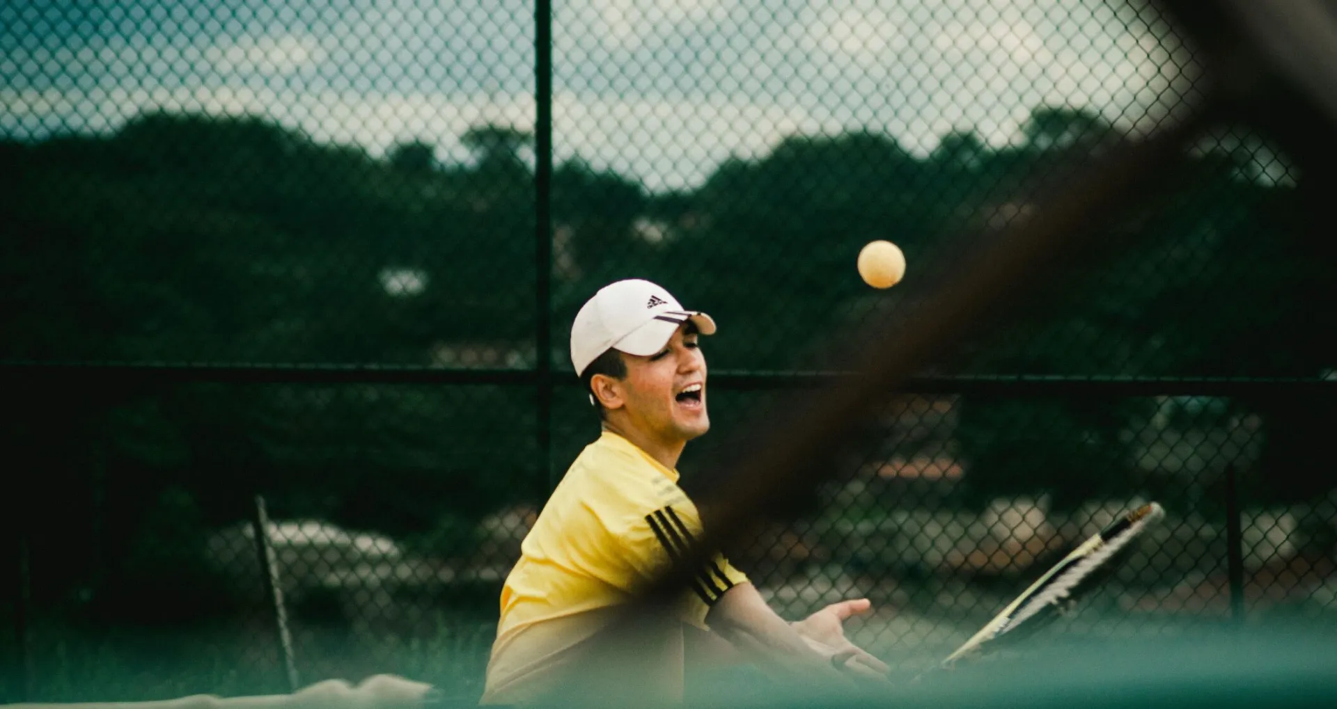 Dynamic action shot of a young man playing tennis on an outdoor court.
