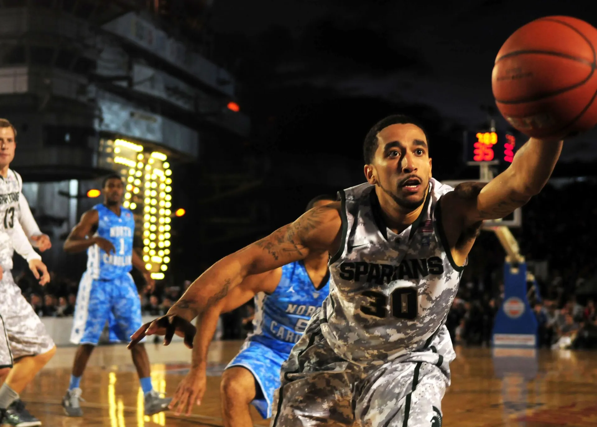 Intense basketball game with athletes in action on an outdoor court during nighttime.