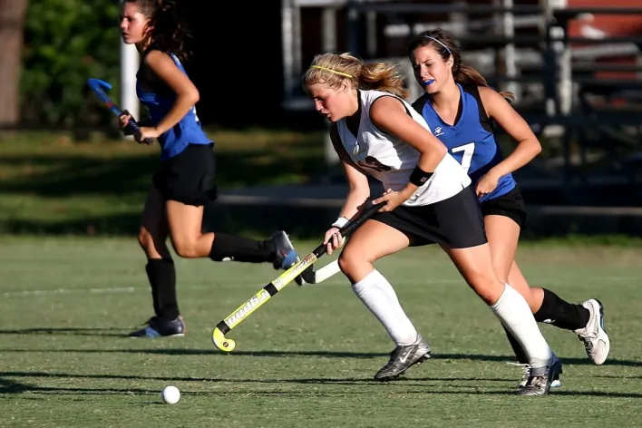 Energetic field hockey game with women players competing outdoors.