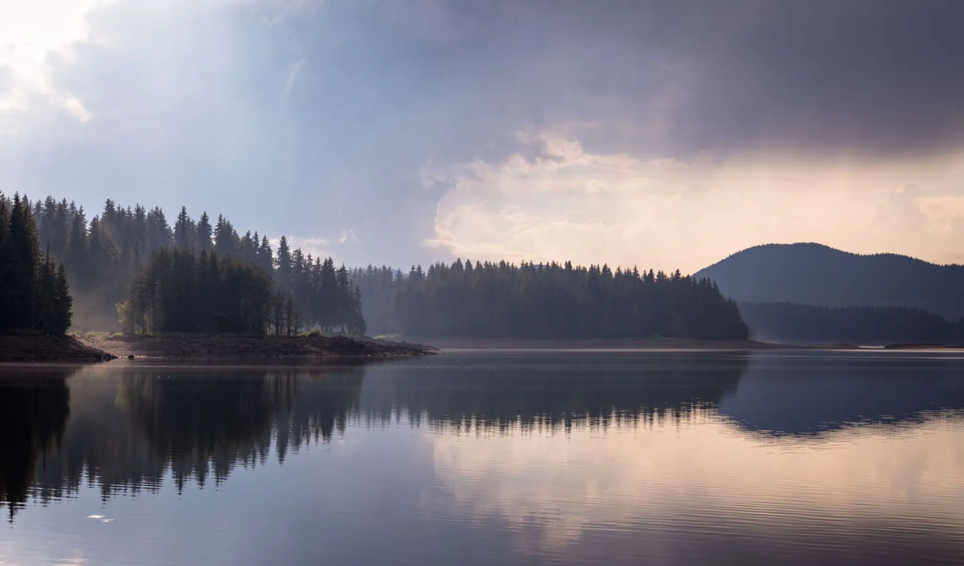 Calm lake with forest reflections at dawn, serene and scenic landscape.