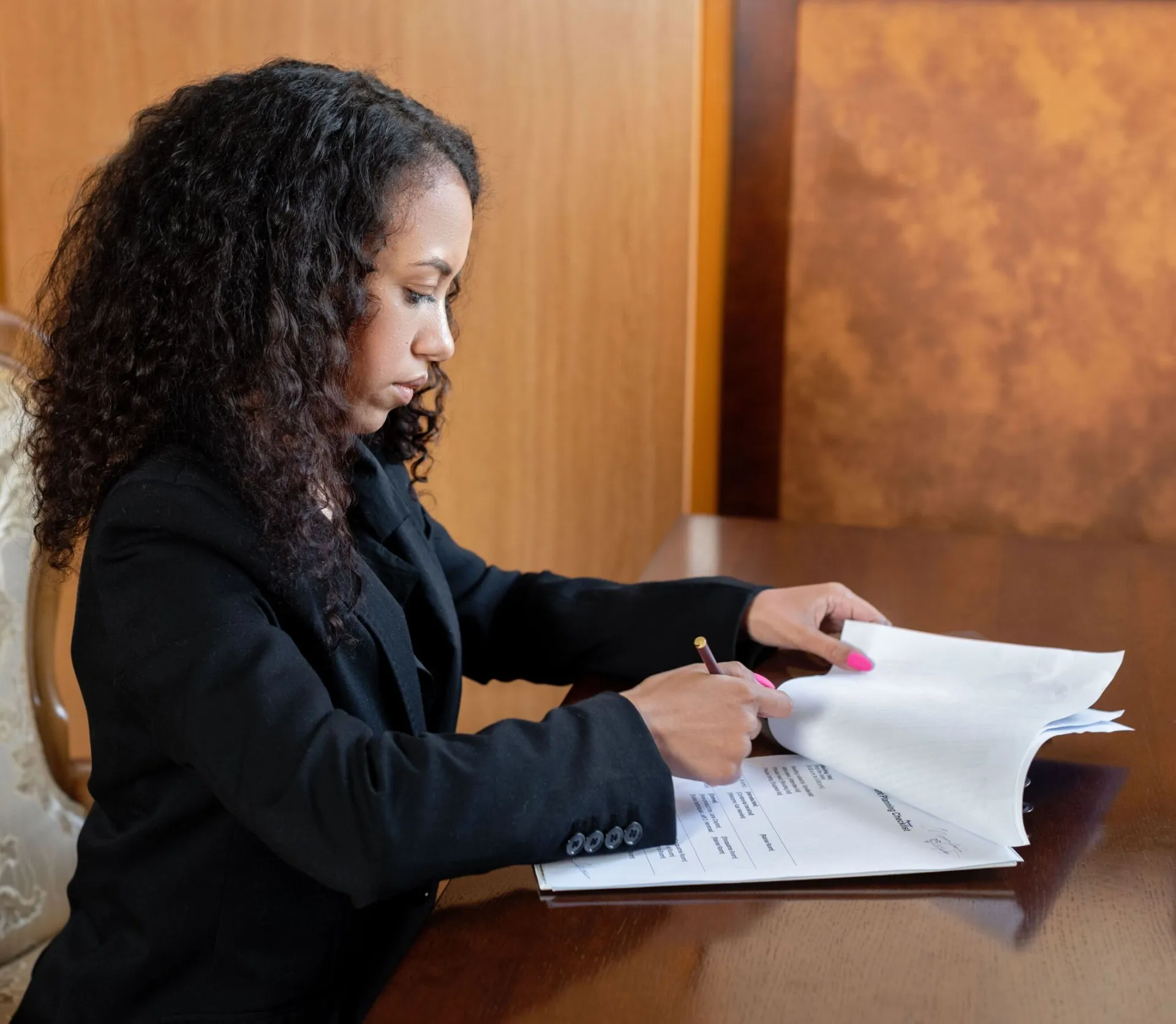 Professional female lawyer with curly hair reviewing legal documents in an office setting.