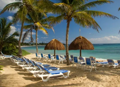 Idyllic beach scene in Akumal, Mexico with sun loungers and palm trees.