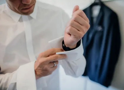 Close-up of a man adjusting his cufflinks, showcasing elegance and style in formal attire.
