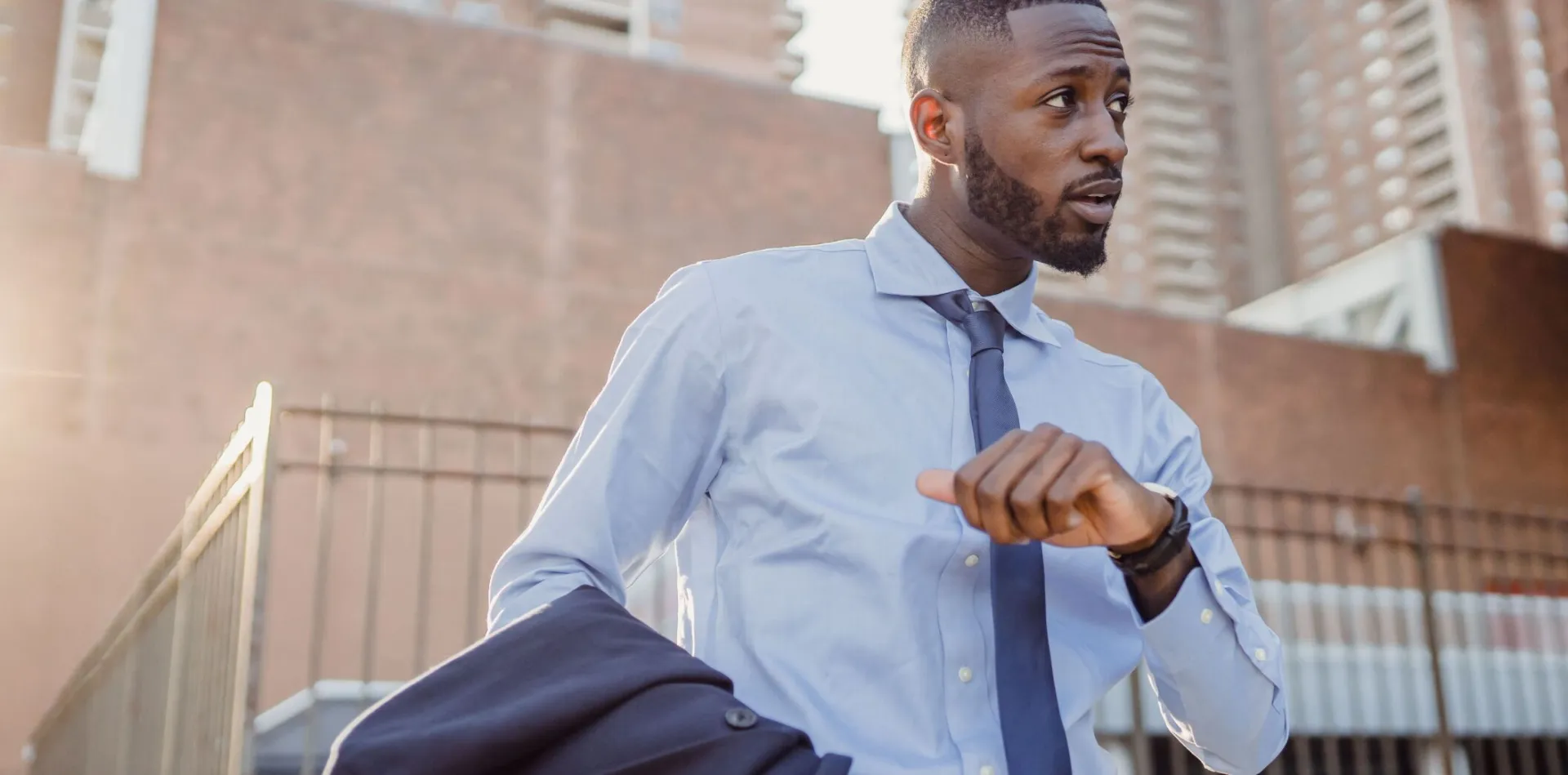 Stylish businessman in city street checking the time, wearing suit and tie.