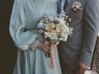 Stylish wedding couple holding a beautiful floral bouquet, symbolizing love and commitment.