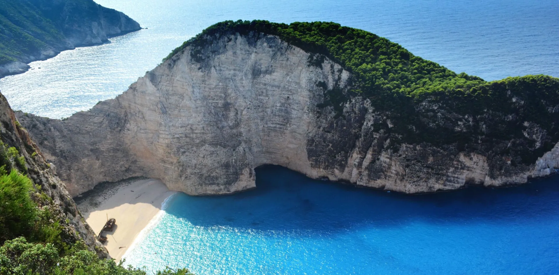 A breathtaking aerial view of Navagio Beach with turquoise waters and lush greenery.