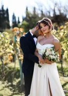 Bride and groom embracing in sunlit vineyard, blissful newlyweds.
