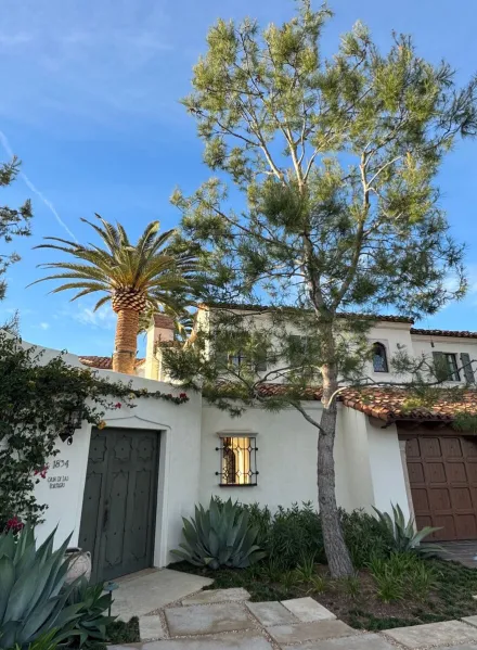 A beautiful Spanish Revival home with palm trees in San Diego, captured on a sunny day.