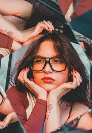 Artistic portrait of a woman with kaleidoscope reflection and glasses.