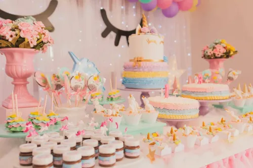 A vibrant unicorn-themed birthday party setup with cakes, cupcakes, and decorations.