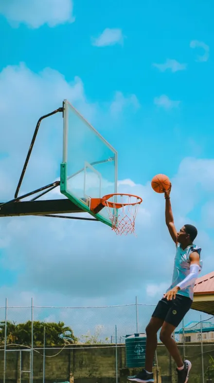 A young man makes an impressive dunk on an outdoor basketball court in Lagos, Nigeria.