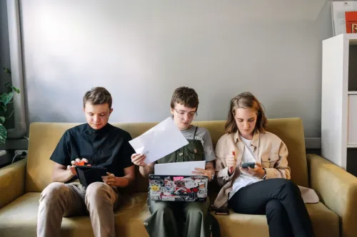 Three young adults concentrating on work in a collaborative office setting.
