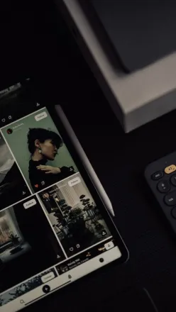 Modern workspace with digital tablet and keyboard featuring social media photos.