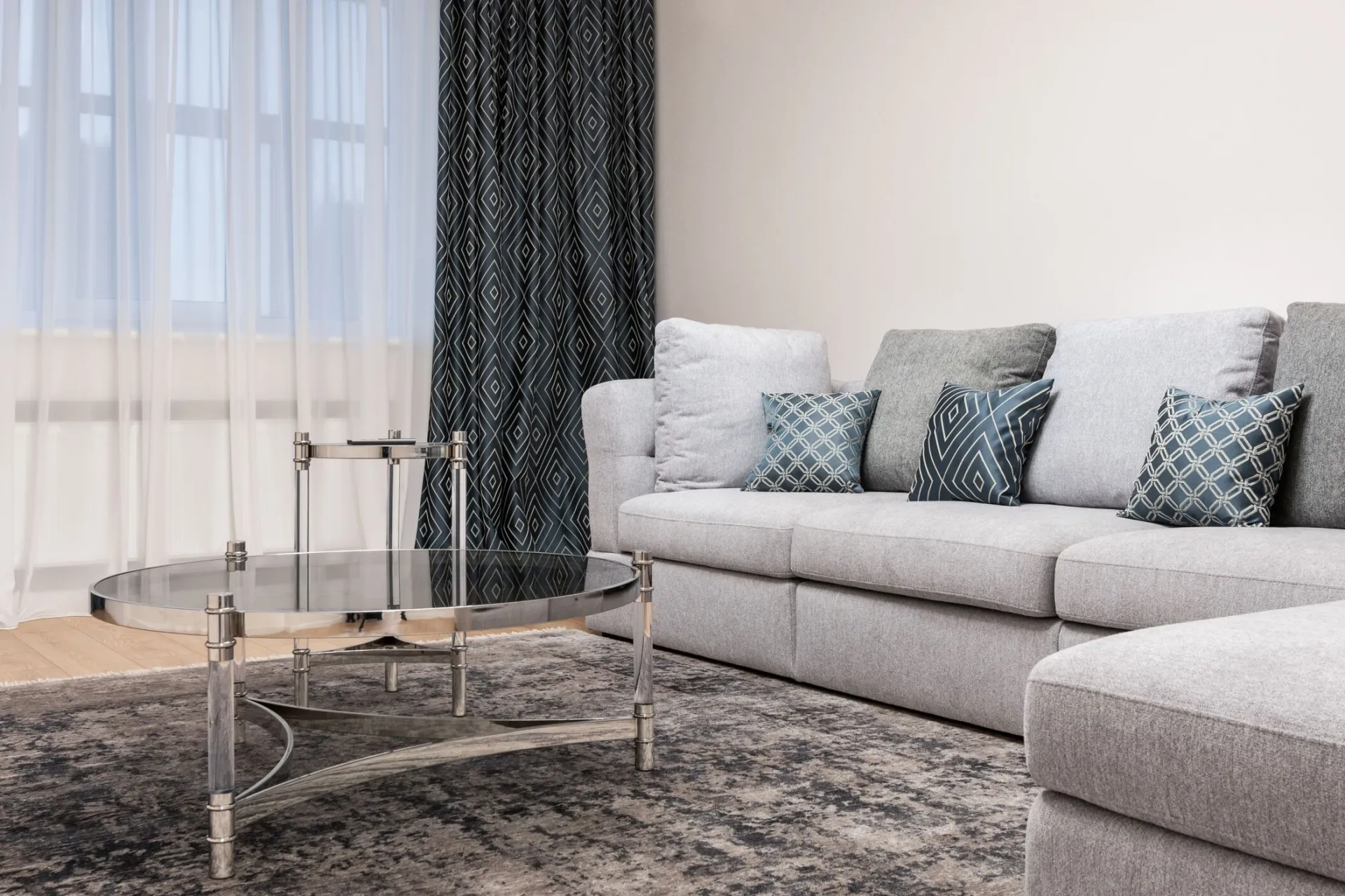 Couch with decorative cushions against metal and glass tables on rug in light house room