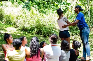 Diverse group participating in an outdoor team building exercise in a lush green setting.