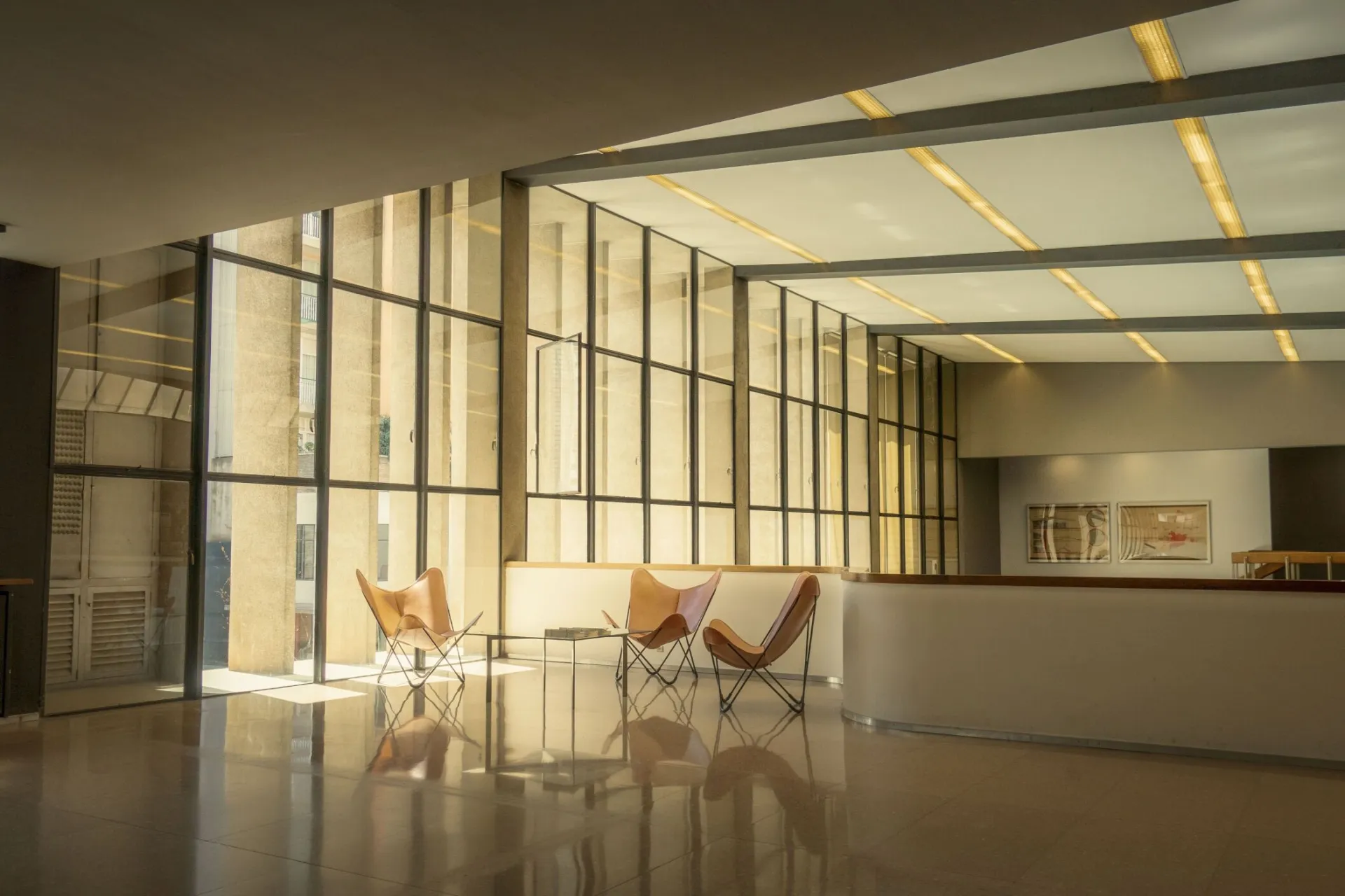 Spacious modern interior with sunlit minimalist design featuring chairs and large windows.