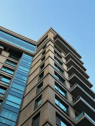 A contemporary high-rise building with glass windows under a clear blue sky.