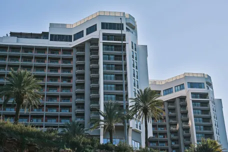 Contemporary hotel building exterior in Antalya, Turkey, featuring modern architecture and palm trees.