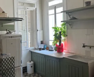 A charming vintage kitchen with retro appliances and natural light through tall windows.