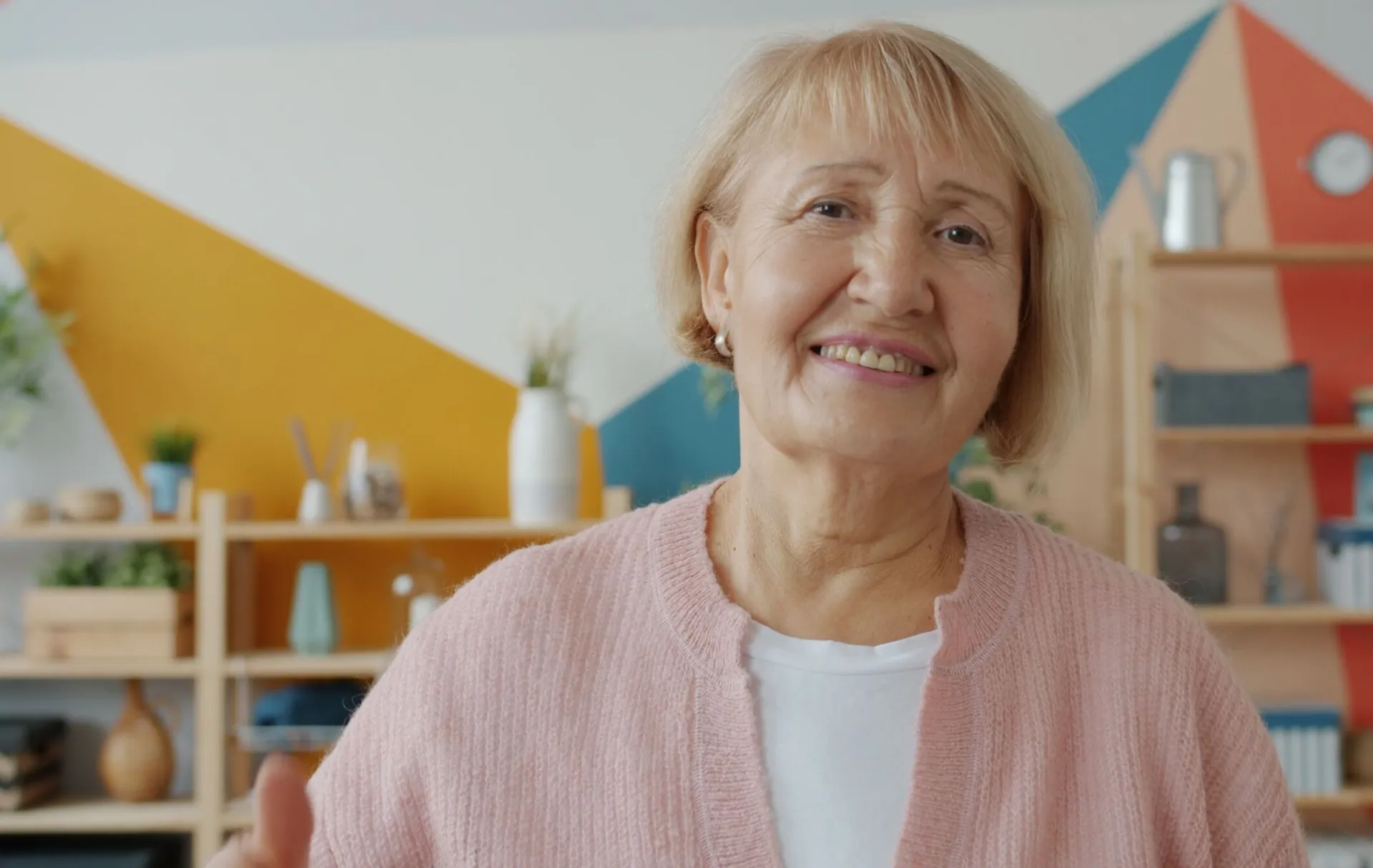 Portrait of a senior woman smiling indoors with colorful background.