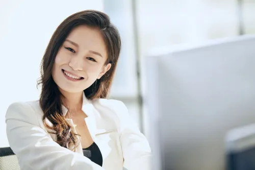 Close-up of a smiling woman in an office, conveying professionalism and positivity.