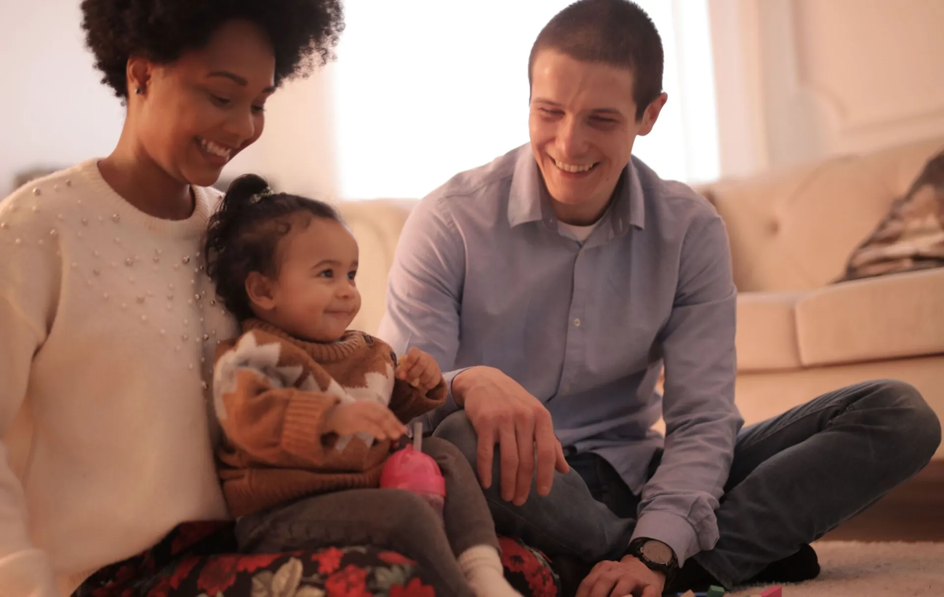 Cheerful family enjoying quality bonding time indoors with their smiling toddler.