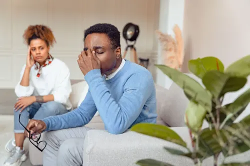 Man in blue sweater looking distressed during a therapy session indoors.