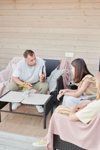 Family enjoying a casual conversation indoors, seated around a coffee table in a modern living room.