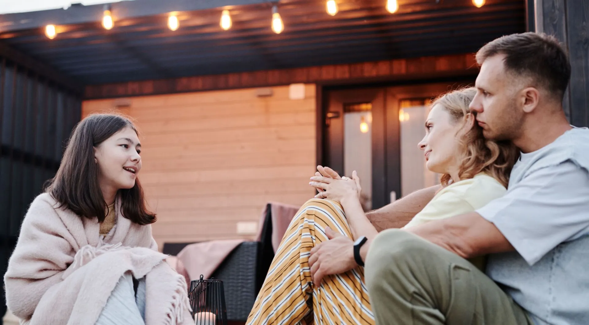 Family enjoying a warm conversation on a cozy patio in the evening.
