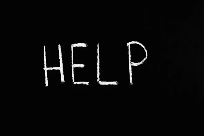 Chalk-written 'HELP' on a deep black background symbolizes assistance and encouragement.